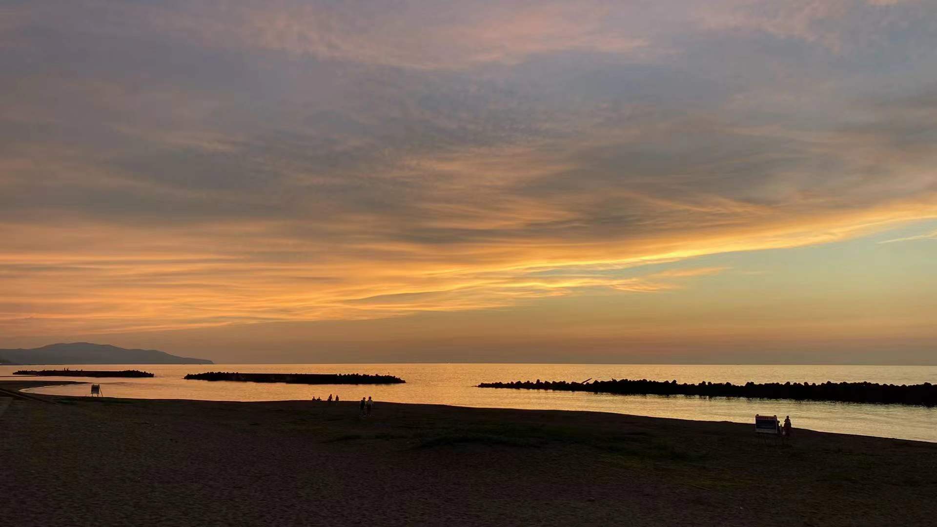 People standing on a beach in Jōetsu at sunset